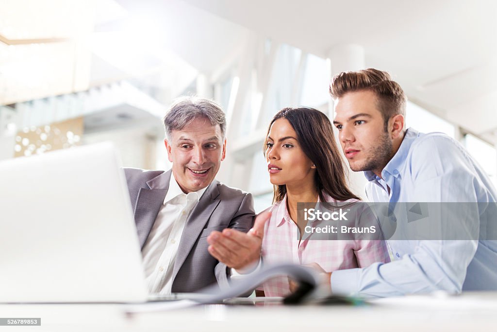 Meeting with financial advisor. Three business people sitting in the office and communicating while using computer. Adult Stock Photo