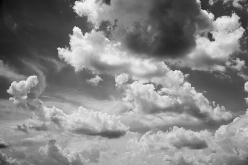 A black and white photograph of cumulus clouds which are fluffy and dramatic.