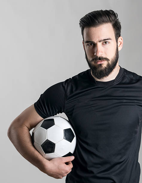 istock Confident soccer player wearing black jersey holding ball under arm 526823420