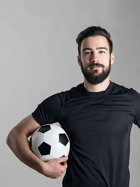 istock Friendly smiling bearded soccer player holding ball under his arm 526823844