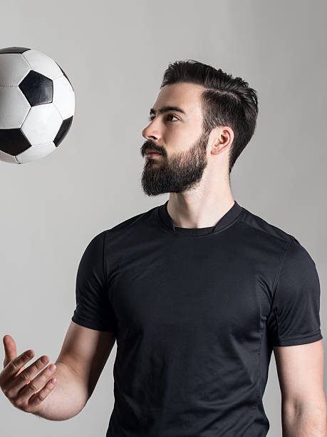 サイドの眺めをかぶり笑うヒゲのある若いサッカー選手投げるボール - throwing football men ball ストックフォトと画像