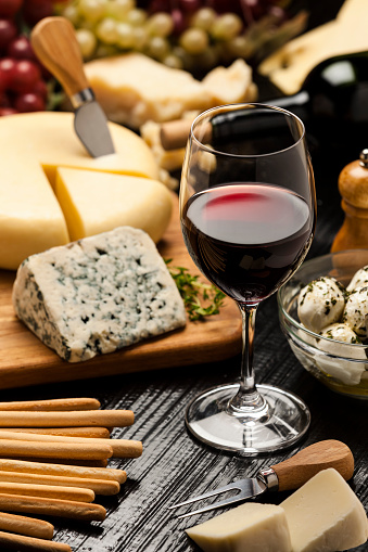 Red wine glass served on a dark table with a selection of cheeses. DSRL studio photo taken with Canon EOS 5D Mk II and Canon EF 70-200mm f/2.8L IS II USM Telephoto Zoom Lens