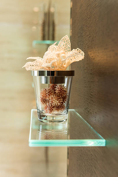 Glass shelf in bathroom with ornaments and decorations, earth tones