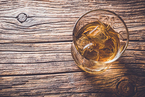 istock Glass of whiskey on wooden table 526825896