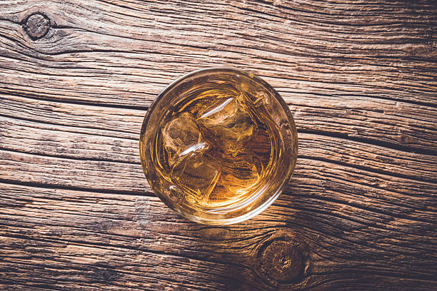 istock Glass of whiskey on wooden table 526825984