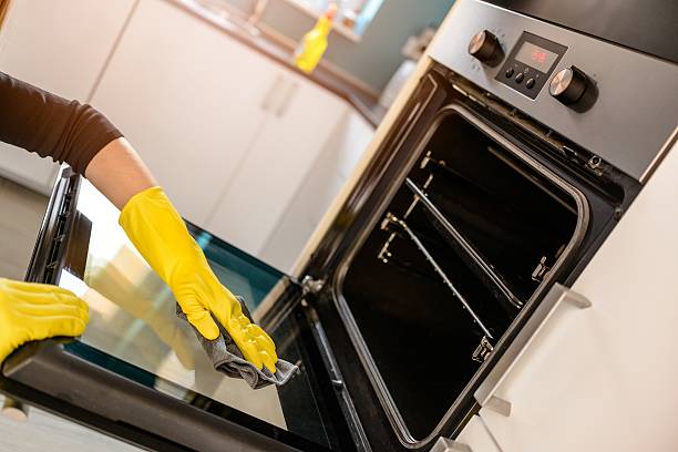 hands in yellow protective rubber gloves cleaning oven