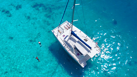 Aerial view of people snorkeling and relaxing on a beatiful Catamaran anchored in clear tropical water in the Caribbean