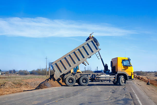 tipper unloads sand on the road truck dumps sand on the side of the road during roadworks dump truck photos stock pictures, royalty-free photos & images