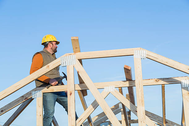 istock Construction worker with hammer on roof of house frame 526829908
