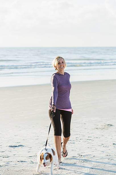 istock Mature woman walking dog on beach 526830046