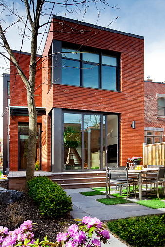 A vertical image of the exterior of a contemporary style townhouse in Spring. Neat and tidy backyard. 