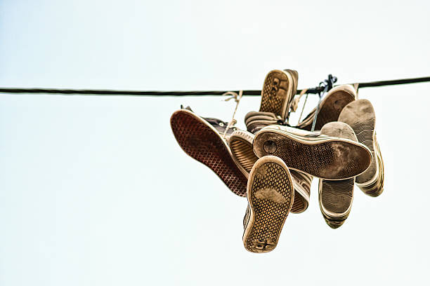 istock Old sport shoes thrown over black cable 526835681