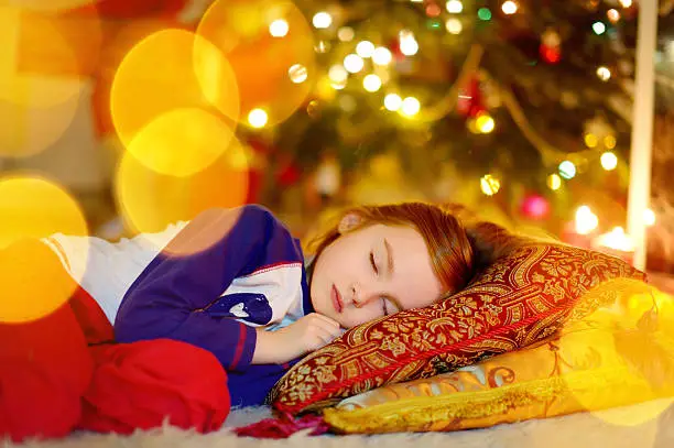 Photo of Little girl sleeping under the Christmas tree