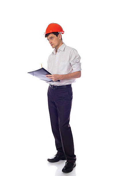 istock Man in a shirt orange construction helmet writes black folder 526836587