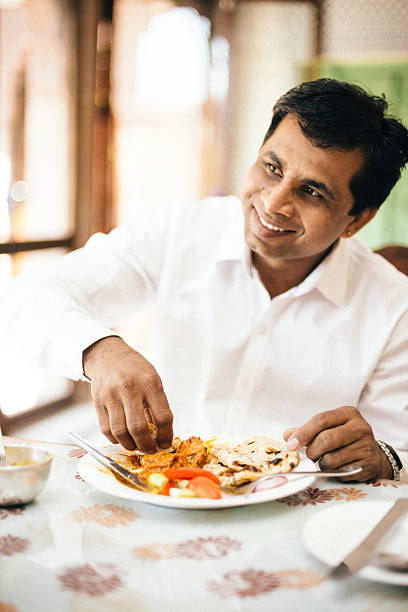 Real Indian man eating with hands in Indian Restaurant Real Indian man eating with hands in indian Restaurant. healthy indian food stock pictures, royalty-free photos & images