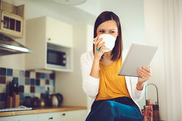 istock Young woman reading tablet and sipping coffee in the kitchen 526837467