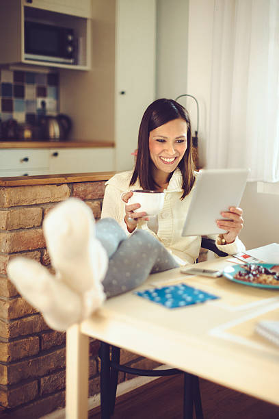 istock Young woman reading tablet and having coffee in the kitchen 526839275