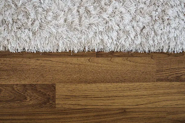 Photo of Close up fluffy luxury carpet on laminate wood floor