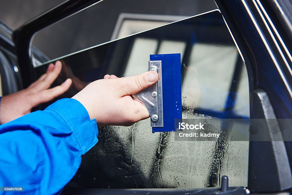 car tinting. Automobile mechanic technician applying foil car tinting. Automobile mechanic technician applying foil on  window in repair garage workshop Car Stock Photo