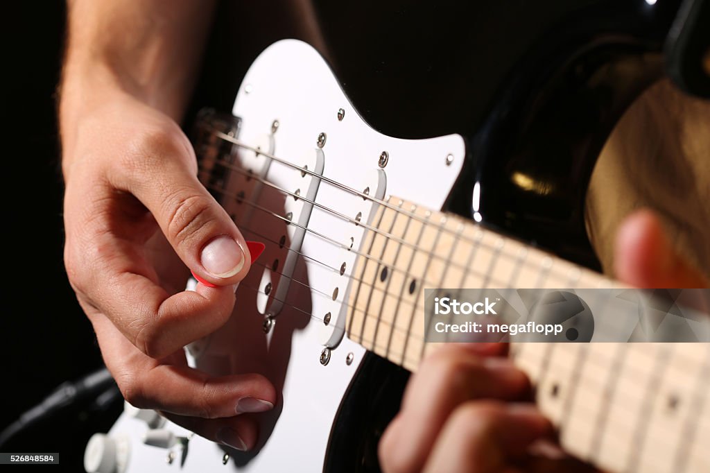 Male hands playing electric guitar with plectrum closeup Male hands playing electric guitar with plectrum closeup photo. Learning musical instrument, music shop or school, blues bar or rock cafe, having fun enjoying hobby concept Electric Guitar Stock Photo