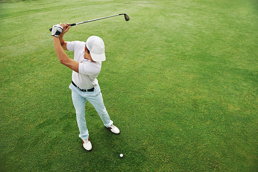 High overhead angle view of golfer hitting golf ball on fairway green grass