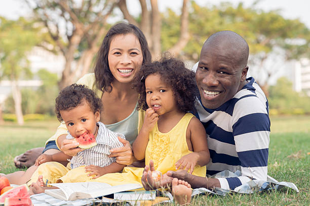 Family picnic Happy family of four having picnic in the park black man eating watermelon stock pictures, royalty-free photos & images