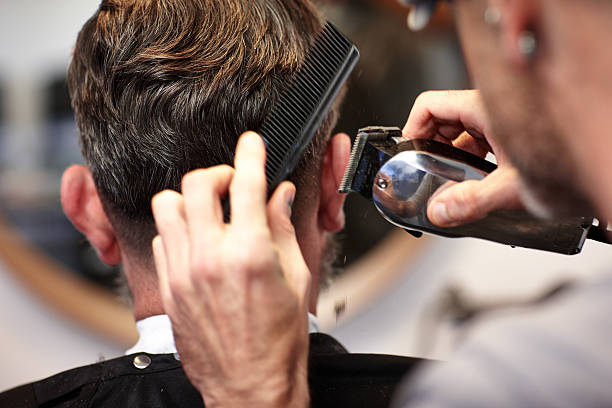 hombre hacer su corte de cabello en el salón - barbero peluquero fotografías e imágenes de stock