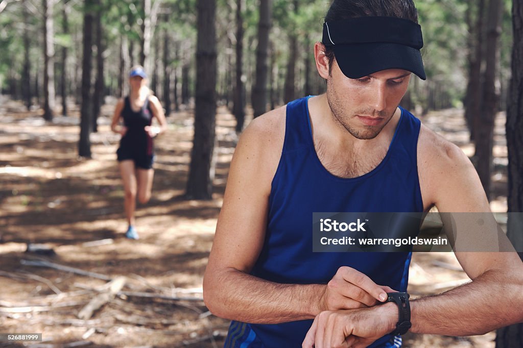 sports watch couple Trail running couple check time on their GPS watch for tracking pace Activity Stock Photo