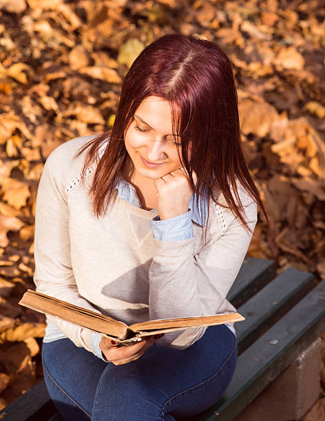 istock Girl sitting on bench in ark and reading a book 526883701