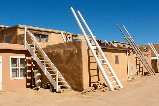 A street scene in Acoma Pueblo (Sky City), New Mexico, a Native American pueblo dating back to the 13th century. Traditional kiva ladders to enter via the roof are placed against the sides of buildings though nowadays there are doors at street level. Some copy space available.