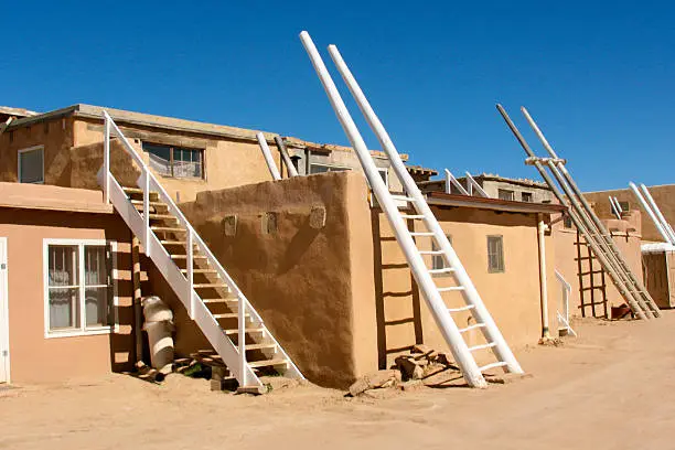 A street scene in Acoma Pueblo (Sky City), New Mexico, a Native American pueblo dating back to the 13th century. Traditional kiva ladders to enter via the roof are placed against the sides of buildings though nowadays there are doors at street level. Some copy space available.