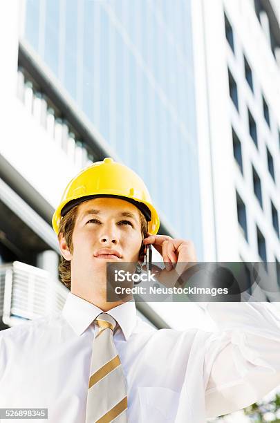 Confident Businessman Answering Call On Smart Phone At Construct Stock Photo - Download Image Now