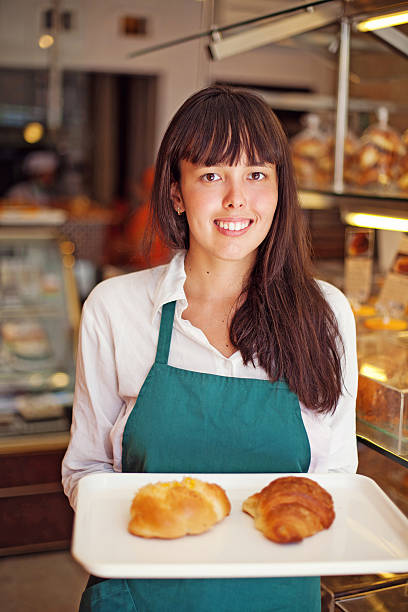 istock Woman in a bakery holding a tray with buns 526917235