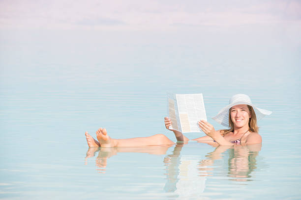 istock Relaxed woman reading newspaper while floating in Dead Sea water. 526920497