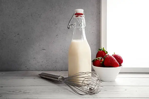 Fresh milk,cream bottle on window sill with strawberries