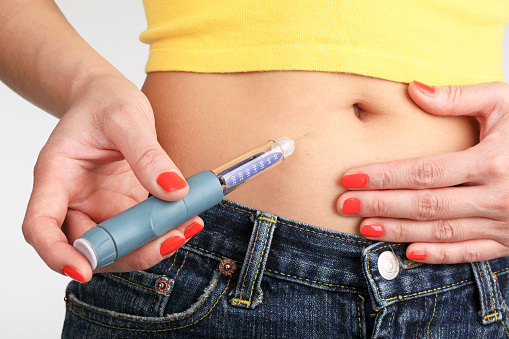 Mujer joven s'inyectarse insulina con una pluma de insulina photo