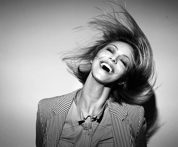 Funky,tousled,fashion. Portrait of adult woman headbanging. She's smiling with her eyes closed and facing camera. Wearing smart casual clothes and standing in front of white wall. Black and white image. tangled photos stock pictures, royalty-free photos & images