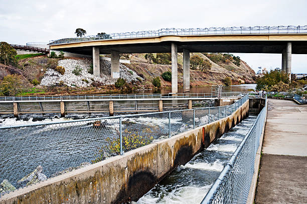 This fish ladder is on the American River in Rancho Cordova a suburb of Sacramento for assisting with the spawn of Salmon. Nimbus dam is in the background with and the water is called the forebay of the dam, During the spawn after a selective number of returning salmon enter the forebay their is a gate placed across the river leaving an opening for the fish to swim towards and up  the ladder and eventually into the hatchery where the eggs are harvested and fertilized. Camera is Nikon D3.