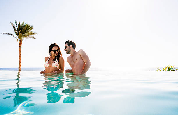 istock Smiling couple flirting at infinity pool. 526945115