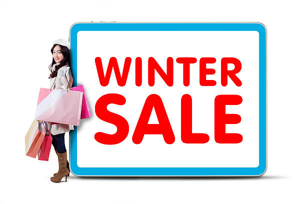 Happy girl in winter clothes holding shopping bags and lean on board with winter sale text