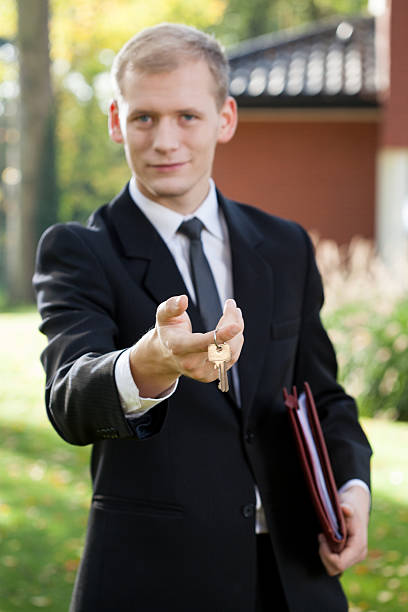 agent immobilier tenant les clés - book holding necktie businessman photos et images de collection