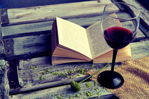 Open book with wine glass on a wooden background