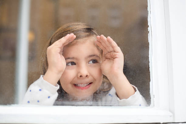 istock Happy little girl looking outside window 526953143