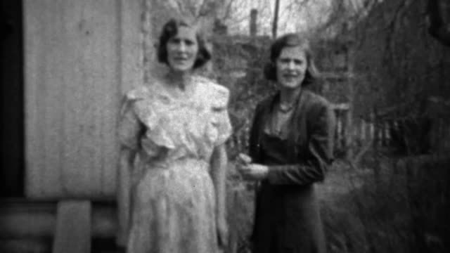 1933: Mother daughter in formal dress play wrestling in front yard.