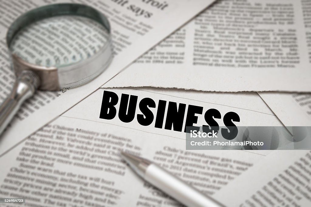 business news business news on newspaper with magnifying glass and pen Analyzing Stock Photo