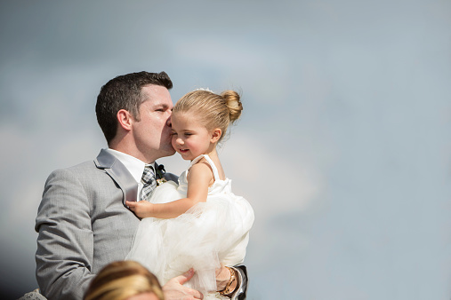 A groom kissing the flower girl-his niece.