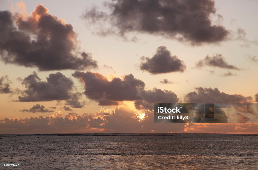 Sun shining through dark Clouds at Sunset Sun shining through dark Clouds at Sunset over South Pacific Ocean - Rarotonga, Cook Islands, Polynesia Horizon Stock Photo