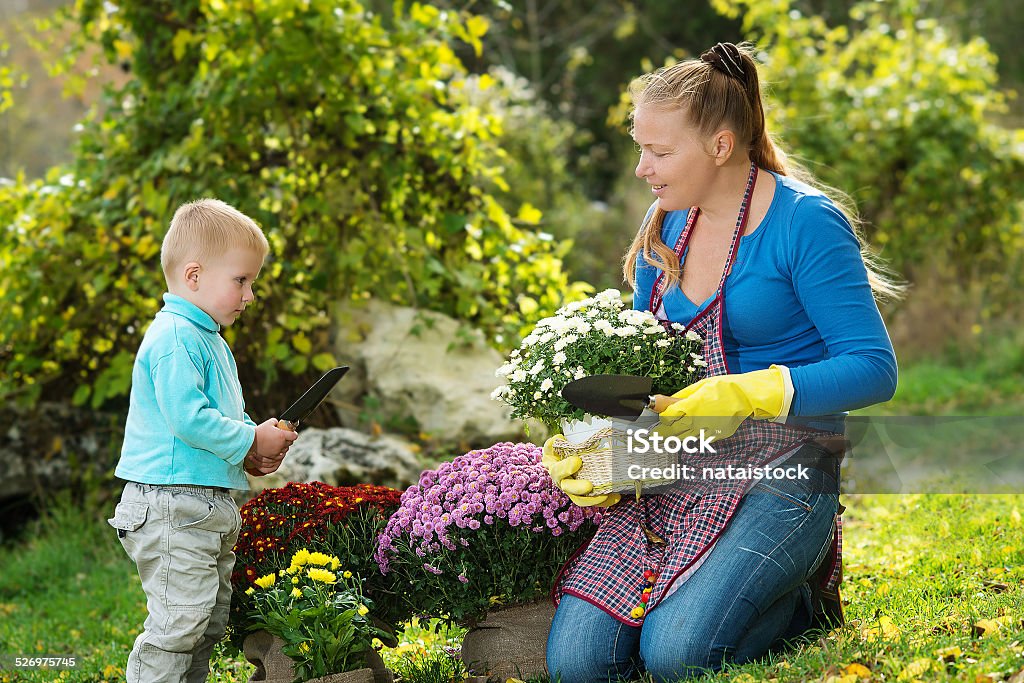 Young woman with a child Young woman with a child are planting flowers in the garden Adult Stock Photo