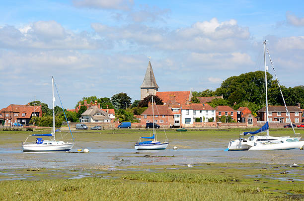 Bosham at low tide. Sussex. England Village of Bosham in Chichester Harbour. West Sussex. England. Low tide with beached boats. People in distance chichester stock pictures, royalty-free photos & images