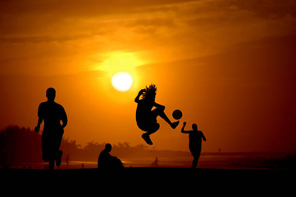 Playing footbal at the sunset on the beach